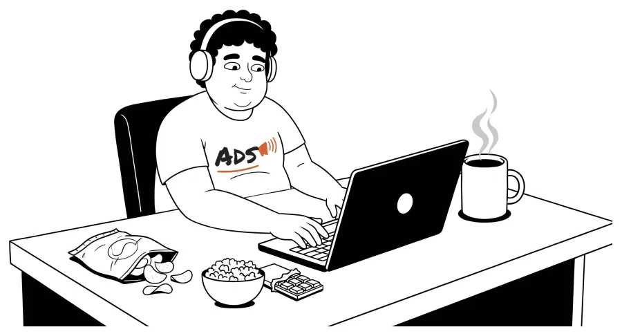 Ads, in headphones, working on his laptop with snacks and a coffee on the desk